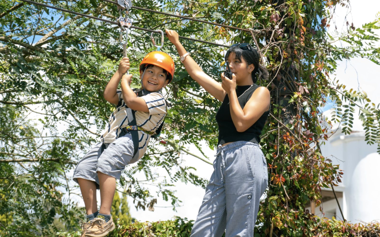 Niño con casco y arnés en el canopy de Vertika Entertainment en Ciudad Cayalá, acompañado por una operadora